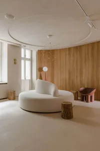Modern living room featuring a round sofa, wooden paneled walls, and a whimsical light fixture.