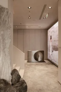 Modern retail store interior with metallic sculpture, cement floor, and minimalist design.