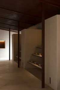 極簡室內空間，混凝土牆面與展示小碗的層架。
