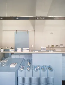 A minimalist retail storefront painted blue with various products displayed.