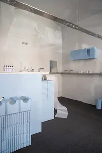 Modern storefront with blue accents, featuring concrete, glass, and metallic elements.