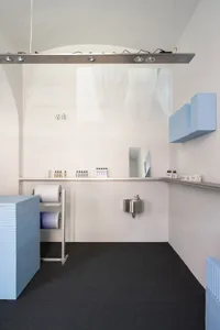Modern, minimalist salon interior with concrete walls and blue tiles on the floor and shelves.