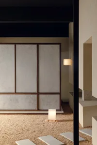 簡約室內空間，白牆覆蓋紋理紙張，單盞桌燈散發溫暖光暈