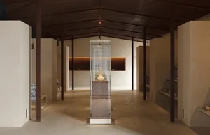 Modern museum exhibition featuring a glass case displaying a vase