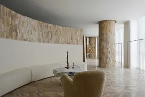 A modern storefront designed with concrete elements, featuring a curved wall and a circular wooden pillar.