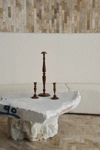 A modern marble coffee table with three wooden candle holders in a living room setting.
