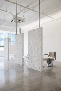 Minimalist commercial interior with concrete walls and floors, featuring modern furniture.