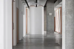 Modern corridor featuring concrete columns and white walls.