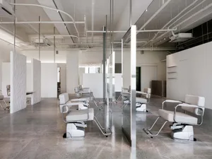 Modern, industrial-style hair salon with minimalist design, metal and leather furnishings, and concrete flooring.