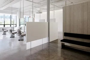 Modern minimalist salon interior design with white walls, grey floors, and white chairs.