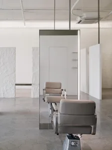 Modern spa interior with minimalist design featuring sleek, neutral-colored leather furniture and a large wall mirror.