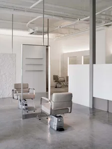 A modern industrial hair salon interior with concrete walls and minimalist design.