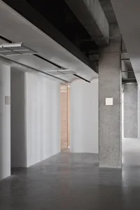 A sleek, minimalist office lobby with concrete walls and a concrete floor.