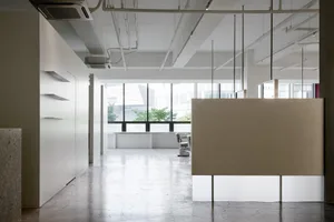 A modern office space with a concrete floor, large windows, and minimalist decor.
