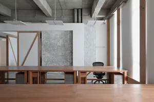 Modern minimalist office space with wooden furniture and concrete walls.