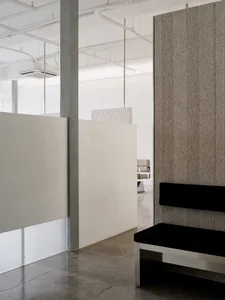 Modern industrial office space with concrete walls, minimalist design, and black seating areas.