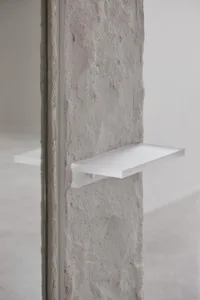 Photographic rendering of a minimalist interior featuring a concrete floating shelf.