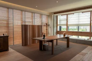 A minimalist living room featuring wooden furniture, large windows, and a serene atmosphere.