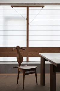 Minimalist interior design featuring a wooden table and simple chair with a wooden hanger.