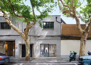 A street view featuring a building with concrete, glass, and wooden elements.
