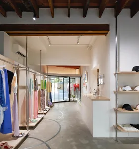 A clothing retail store with concrete walls, glass display cases, and wooden accents.