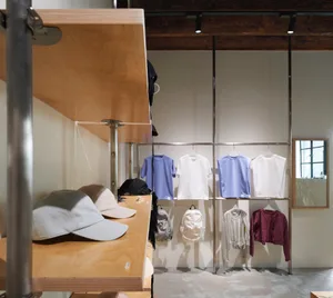 A modern retail store with metallic shelves displaying various clothing items and accessories.