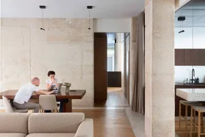 A minimalist, modern residential interior featuring exposed concrete walls and a spacious living area.
