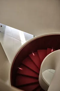 A red carpet winding staircase in an industrial setting.
