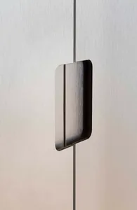A minimalist metal handle mounted on a brushed aluminum surface.
