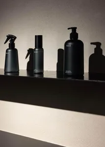 Modern black bathroom accessories with glass material on a sleek black shelf.