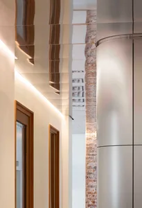 An industrial-style corridor with steel ceiling panels and exposed brick walls.