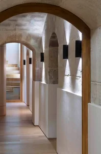 A modern interior corridor with concrete walls and illuminated arches.