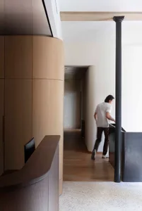 A modern office space featuring wooden panels, concrete walls, and black metal elements.
