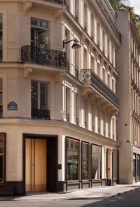 The facade of a stone building with metal railings on a Parisian street.