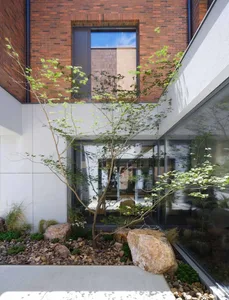 Modern residential entry with brick walls, glass windows, and rock landscaping.