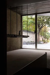Interior view of a modern building with a large window showcasing a view of trees and buildings outside.