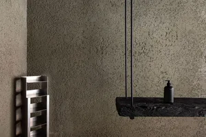 Modern bathroom with textured concrete walls, metal radiator, and rustic wooden shelf.