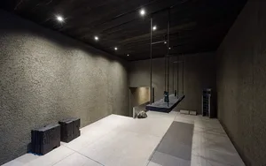 Minimalist art installation featuring concrete and metal elements hanging from the ceiling.
