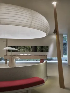 Modern office interior featuring concrete walls and a curved bench with red cushioning.