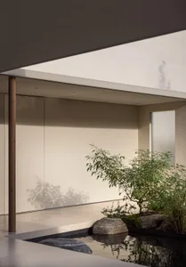 Modern interior with minimalist design, concrete floor, glass walls, and Japanese garden elements.