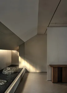 Modern minimalist lobby interior with concrete walls and glass elements.