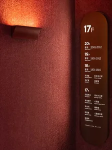 A textured wall with a light fixture and a sign indicating floor numbers and room numbers for hotel suites.