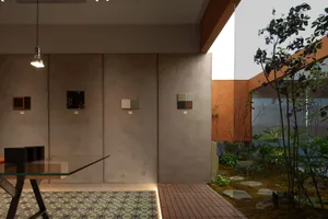 An industrial interior space featuring concrete walls, a patterned floor, and a view of a small garden area with trees and ro
