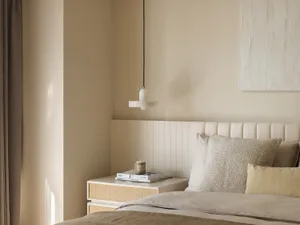 Contemporary minimalist bedroom interior with soft neutral tones, featuring a neatly made bed with white and grey pillows, a