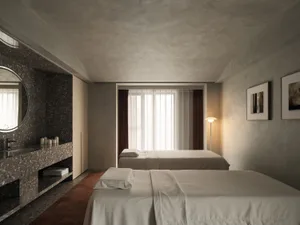 A minimalist bedroom featuring a bed with white bedding and a terrazzo sink, set against a textured wall and floor.