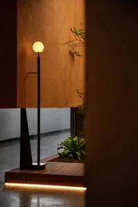 Minimalist interior design featuring floor lamp with warm lighting and wooden plant box.