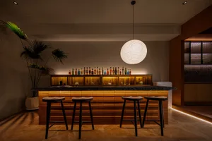 A modern bar with wooden stools and a well-lit, stylish counter.