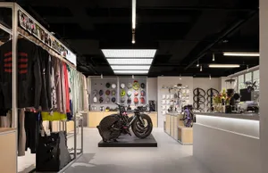 一間融合現代與工業設計元素的自行車店室內，設有服裝展示架與自行車陳列區。