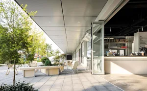 Modern exterior of a coffee shop with glass walls and seating area.
