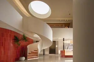 Modern commercial space with red tile and white concrete walls, featuring a spiral staircase.